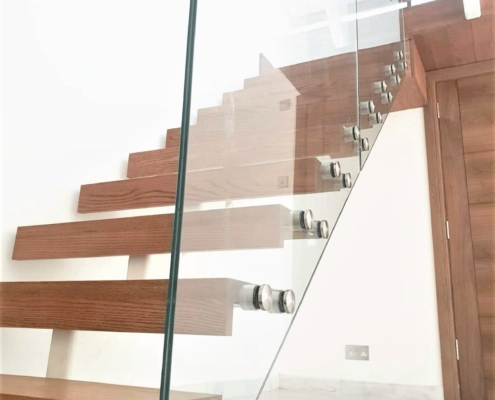 Staircase with walnut stained Oak and frameless glass to one side of the stairs